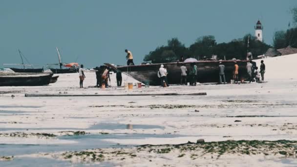 Massor av lokala afrikanska fiskare nära Wooden Fishing Boat Dhow på en sandstrand — Stockvideo