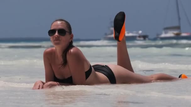 Jeune femme en bikini noir bronzage sur une plage de sable blanc Paradise se trouve près de l'océan — Video