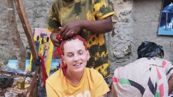 Afrikanske kvinde vævning afrikanske fletninger med rød Kanekalon udendørs, Zanzibar Afrika – Stock-video