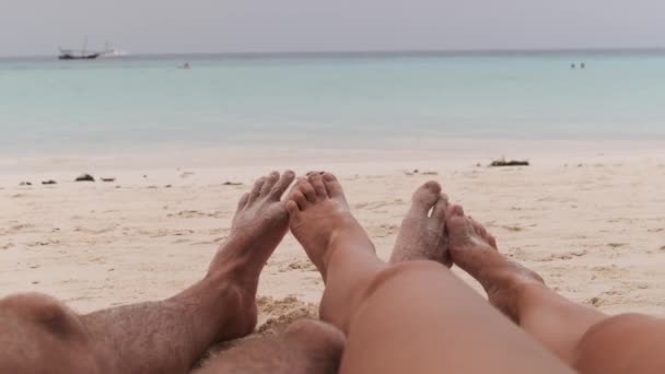 海によって熱帯の砂浜に横たわっている男性と女性のカップルのPOV足 — ストック動画