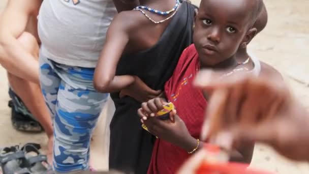 Miejscowy afrykański głodny dziecko zjada papier na ulicy wśród ludzi, Zanzibar, Afryka — Wideo stockowe