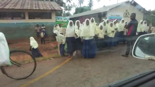 Tłum afrykańskich dzieci szkolnych wybiegają na drogę w lokalnej wiosce, jazdy samochodem, Zanzibar — Wideo stockowe