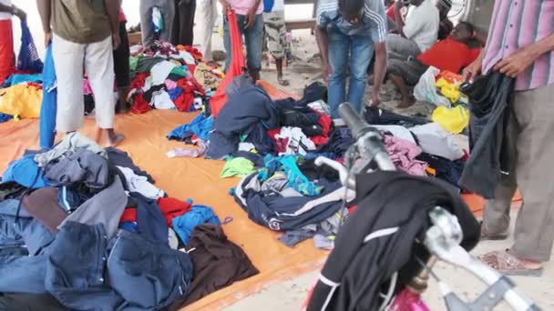 Africanos compran ropa de segunda mano en una tienda al aire libre en África, Zanzíbar — Vídeos de Stock
