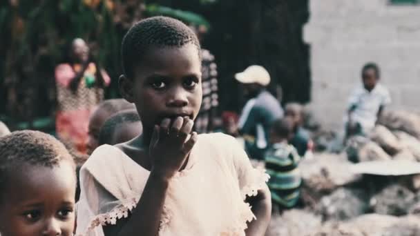 Местная африканская девушка с любопытством смотрит в камеру в деревне Занзибар, Африка — стоковое видео