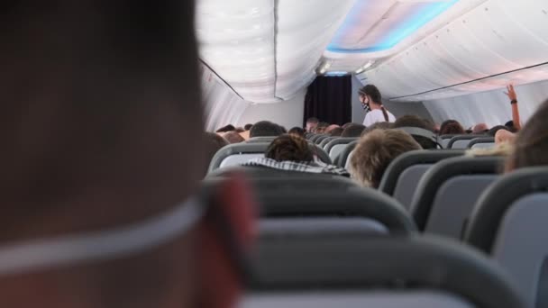 Kabin av passagerarplan med maskerade personer sittande i fåtöljer under flygning — Stockvideo
