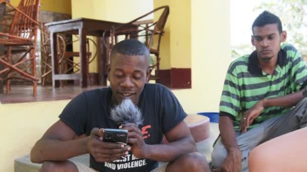 Yerel Afrikalı bir adam kamerada bir blog kaydediyor. Telefon ve mikrofon kullanıyor. — Stok video