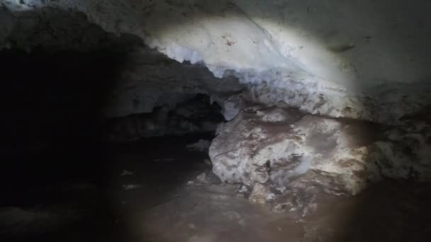 Erkunden Sie eine tiefe dunkle Höhle mit Stalaktiten im Licht einer Laterne, Afrika — Stockvideo