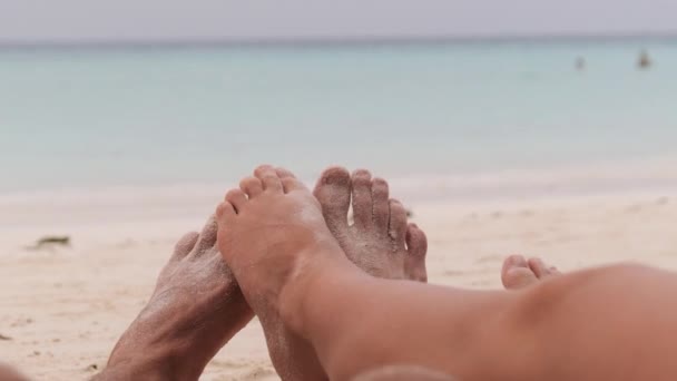 POV Nohy páru mužů a žen ležících na tropické písečné pláži u oceánu — Stock video