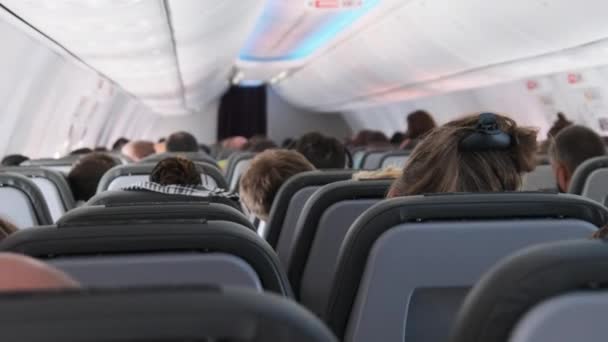 Cabine van passagiersvliegtuig met gemaskerde mensen die in fauteuils zitten tijdens de vlucht — Stockvideo