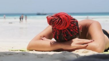 Genç Kadın Cennet 'te güneşleniyor Kumsal Kumsalında Okyanus yakınlarındaki Kırmızı Bikini' de yatıyor