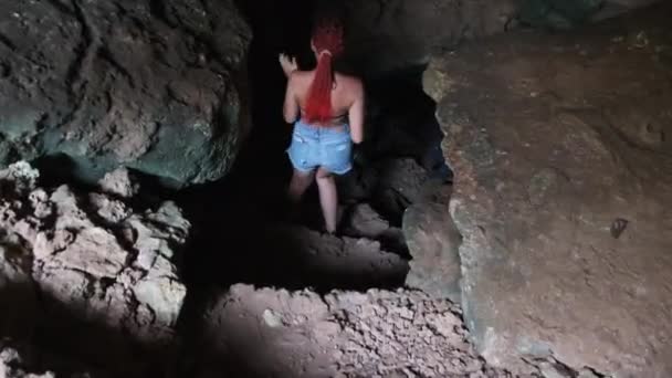 Donna esplora stalattiti all'interno di una profonda grotta oscura, illuminante con torcia elettrica — Video Stock