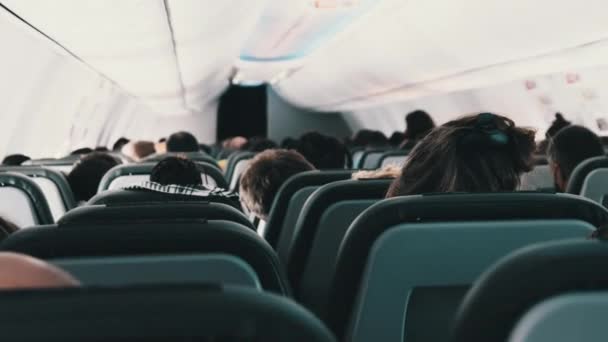 Cabine do avião de passageiros com pessoas mascaradas sentadas em poltronas durante o voo — Vídeo de Stock