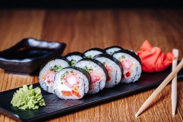 Restoranda ahşap bir masada suşi, lezzetli Japon yemekleri, suşi ruloları.