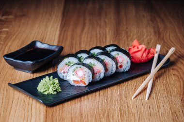Restoranda ahşap bir masada suşi, lezzetli Japon yemekleri, suşi ruloları.