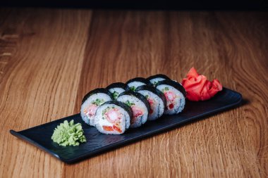 Restoranda ahşap bir masada suşi, lezzetli Japon yemekleri, suşi ruloları.