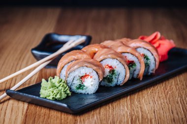 Restoranda ahşap bir masada suşi, lezzetli Japon yemekleri, suşi ruloları.