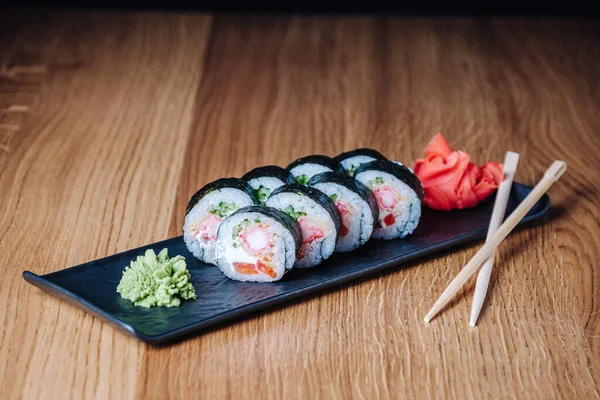 Restoranda ahşap bir masada suşi, lezzetli Japon yemekleri, suşi ruloları.