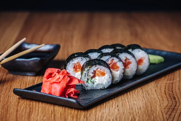 Restoranda ahşap bir masada suşi, lezzetli Japon yemekleri, suşi ruloları.