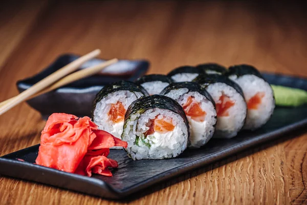 Restoranda ahşap bir masada suşi, lezzetli Japon yemekleri, suşi ruloları.