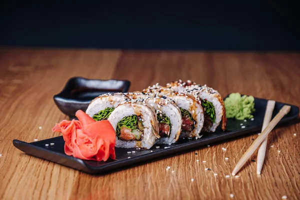 Restoranda ahşap bir masada suşi, lezzetli Japon yemekleri, suşi ruloları.