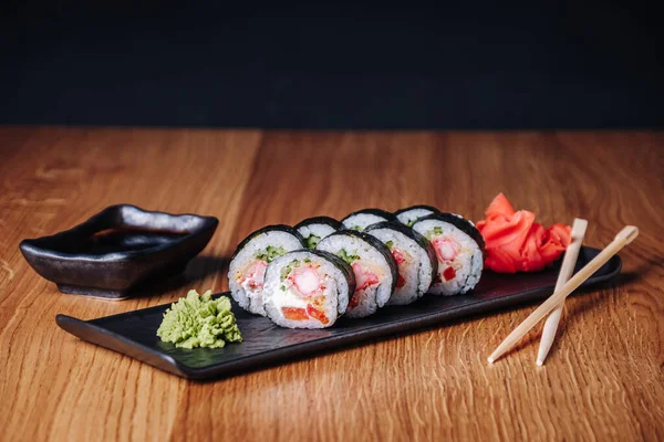 Restoranda ahşap bir masada suşi, lezzetli Japon yemekleri, suşi ruloları.
