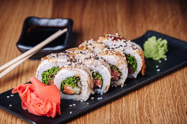 Restoranda ahşap bir masada suşi, lezzetli Japon yemekleri, suşi ruloları.