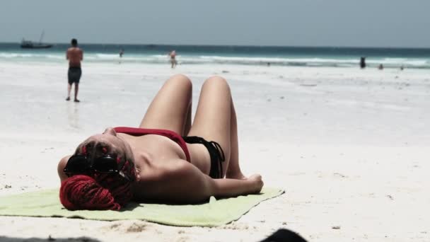 Młoda kobieta opala się na plaży Paradise Sandy Leżąc w czerwonym bikini w pobliżu oceanu — Wideo stockowe