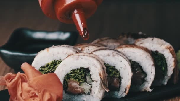 Sushi apetitoso é derramado com molho doce em uma mesa de madeira no restaurante — Vídeo de Stock