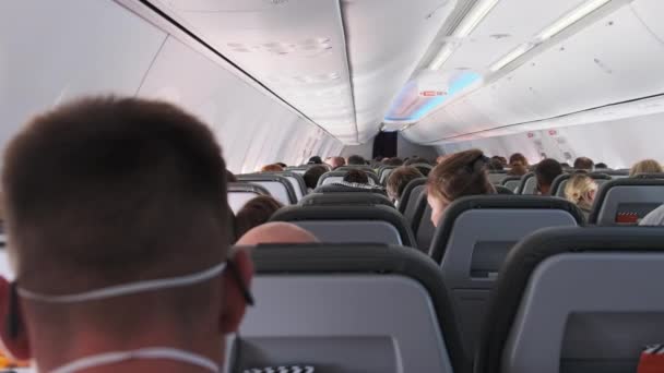 Cabine d'avion de passagers avec des personnes masquées assises dans des fauteuils pendant le vol — Video