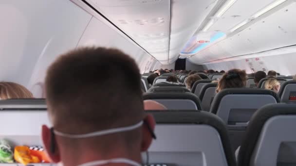 飛行中にアームチェアに座っている仮面の人々と旅客機のキャビン — ストック動画