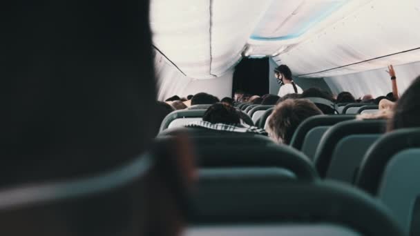 Cabine do avião de passageiros com pessoas mascaradas sentadas em poltronas durante o voo — Vídeo de Stock