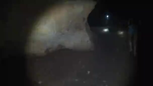 Femme explore stalactites à l'intérieur d'une grotte sombre profonde, éclairant avec lampe de poche — Video