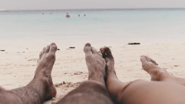 POV Fötter av ett par män och kvinnor som ligger på en tropisk sandstrand vid havet — Stockvideo