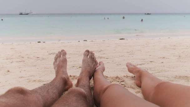 POV Pés de um casal de homens e mulheres deitados em uma praia tropical de areia pelo oceano — Vídeo de Stock