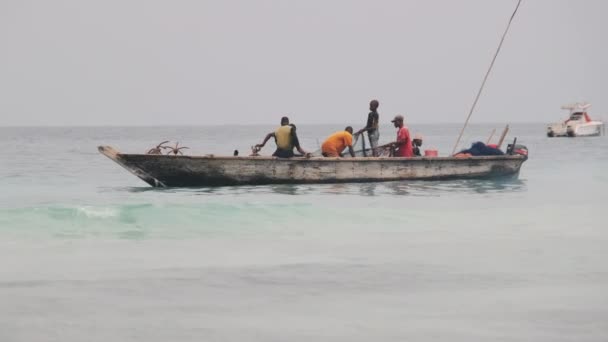 Pescadores africanos em peixes de barco de madeira no oceano usando uma rede de pesca, Zanzibar — Vídeo de Stock