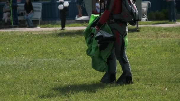 De net geland parachutist met een parachute wandelingen langs de landingsbaan van het vliegveld — Stockvideo