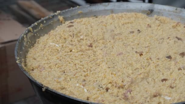 Préparer la bouillie de blé dans un grand chaudron traditionnel au-dessus d'un feu ouvert — Video