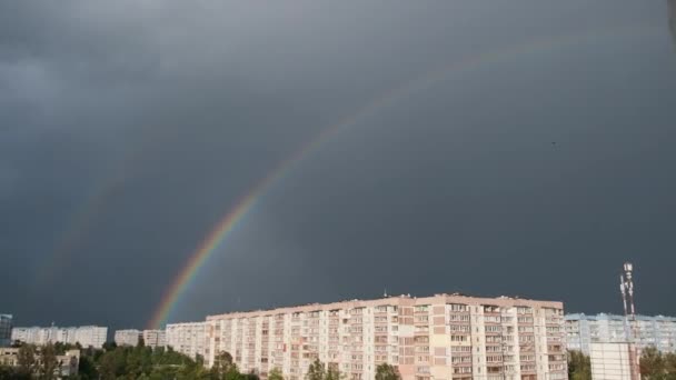 Enorme arco-íris no céu nublado acima das casas na cidade — Vídeo de Stock