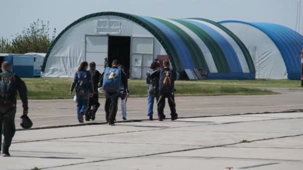 Skupina parašutistů jde do letadla poblíž hangáru na seskok padákem — Stock video