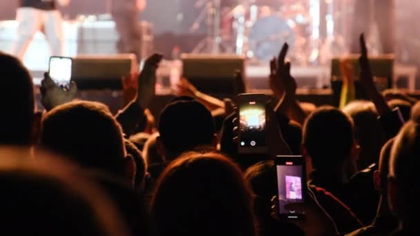 Gente filmando concierto de rock en teléfonos inteligentes, siluetas multitud de fans bailando — Vídeo de stock