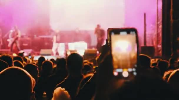 Gente filmando concierto de rock en teléfonos inteligentes, siluetas multitud de fans bailando — Vídeo de stock