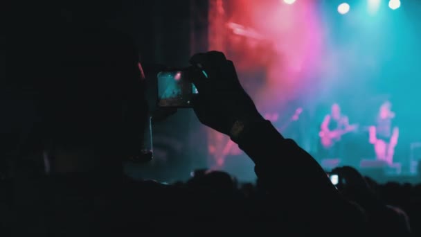 Gente filmando concierto de rock en teléfonos inteligentes, siluetas multitud de fans bailando — Vídeos de Stock