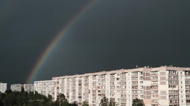 Τεράστιο ουράνιο τόξο στο συννεφιασμένο ουρανό πάνω από τα σπίτια στην πόλη — Αρχείο Βίντεο