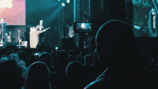 Pessoas filmando concerto de rock em smartphones, silhuetas multidão de fãs dançando — Vídeo de Stock