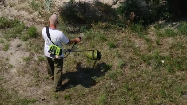 L'uomo falcia l'erba con un tosaerba manuale a benzina — Video Stock