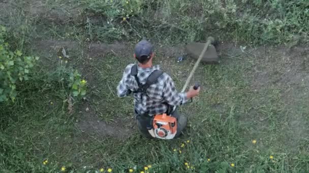 Ο άνθρωπος κουρεύει το γρασίδι με ένα χειροκίνητο χλοοκοπτικό βενζίνης — Αρχείο Βίντεο
