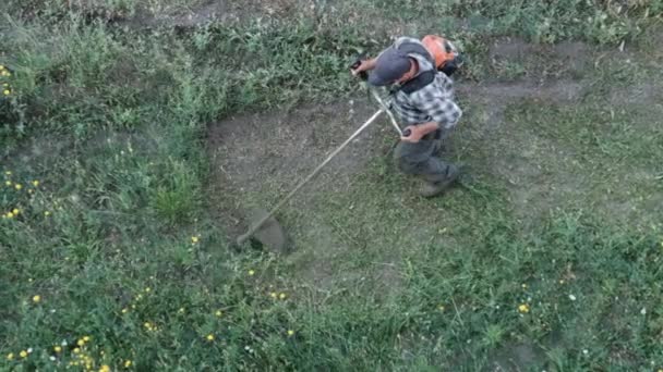 El hombre corta la hierba con un cortacésped manual de gasolina — Vídeo de stock