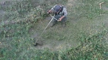 Adam, çimleri elle biçme makinesiyle biçiyor.