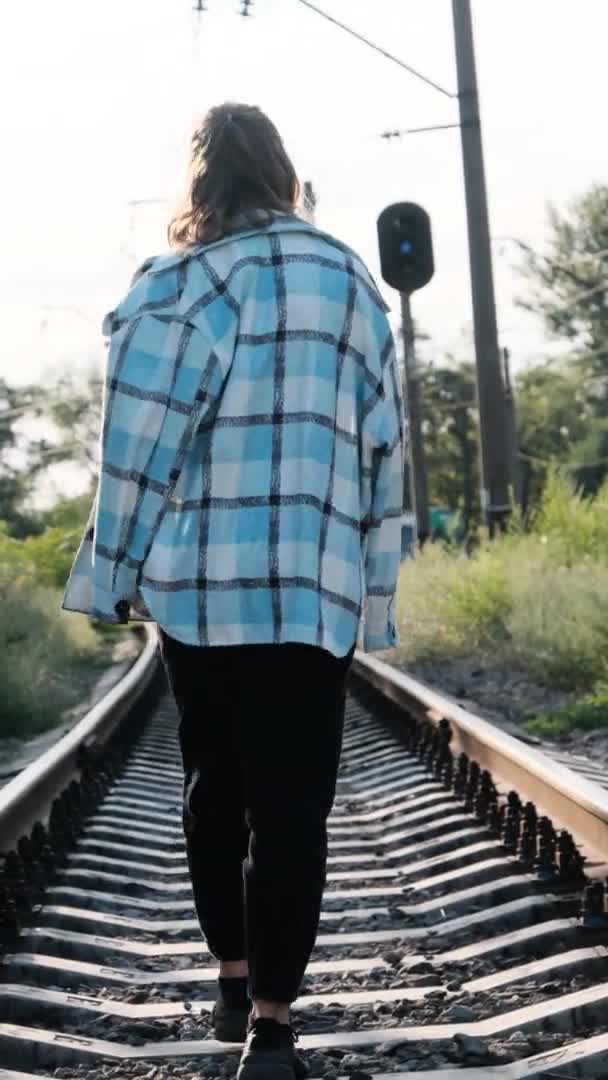 Vídeo Vertical Joven hermosa mujer camina sola en la vía férrea — Vídeos de Stock