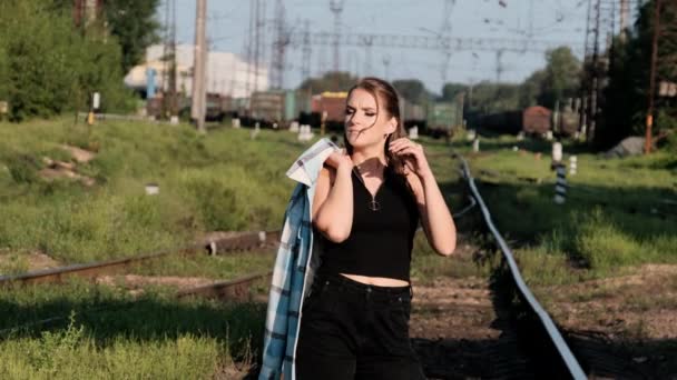 Młoda Seksowna kobieta stoi na torach kolejowych i patrzy w kamerę. — Wideo stockowe